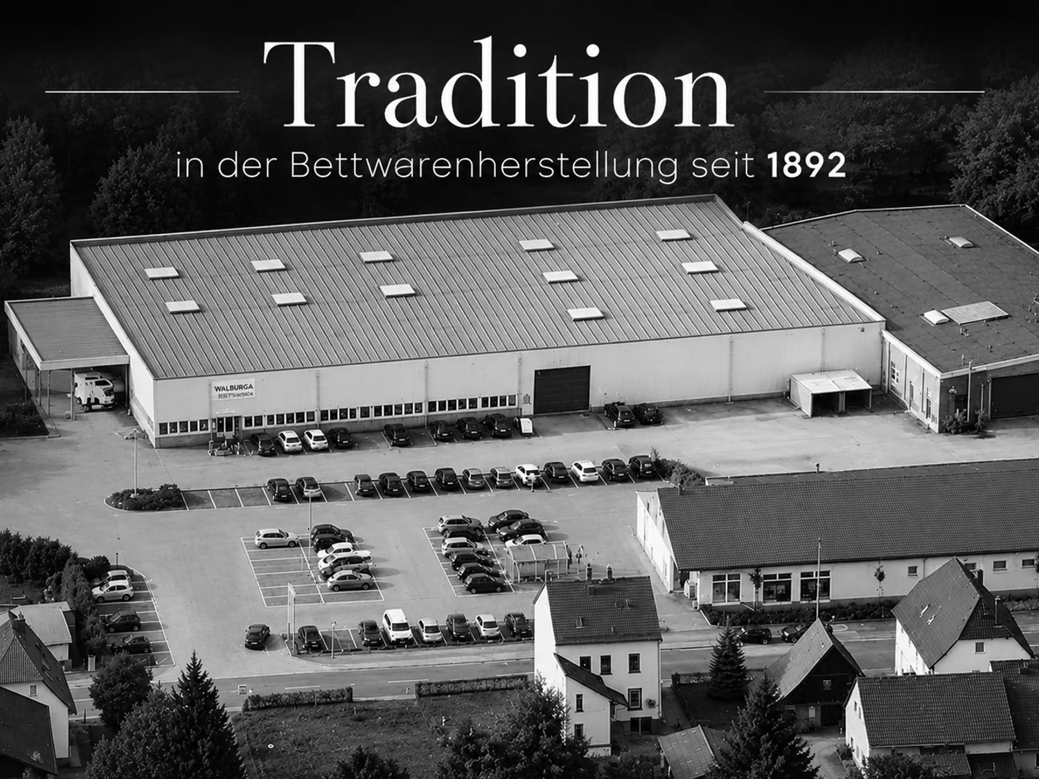 Luftaufnahme der Walburga-Manufaktur in Schwarzweiss mit dem Schriftzug „Tradition in der Bettwarenherstellung seit 1892“